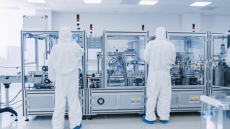 制造实验室的科学家在保护工作服与工业高精度3D打印机械工作。制造制药/技术/工业产品。